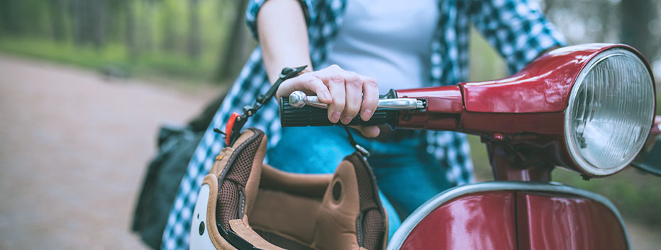 Woman riding red moped on street