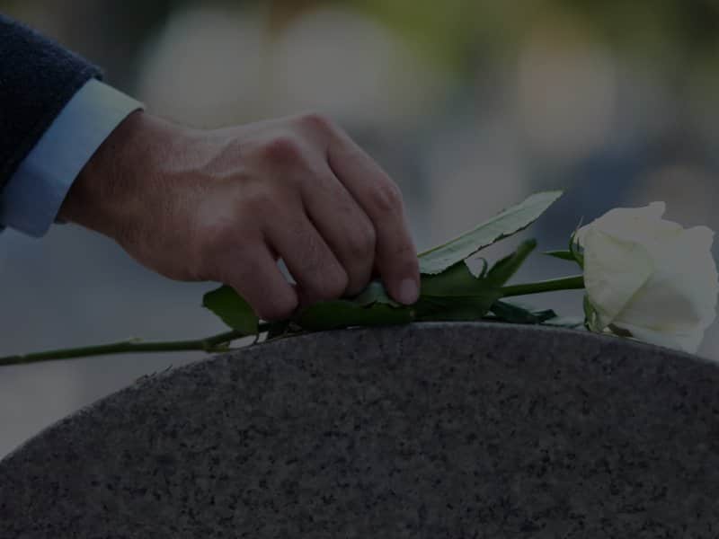 Man placing white rose on tombstone